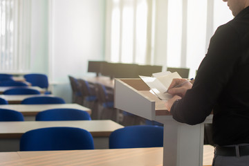 a young male speaker in a black shirt prepares for his speech or conference in an empty audience