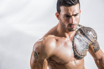 Handsome shirtless muscular man with jeans, standing, on white background in studio shot
