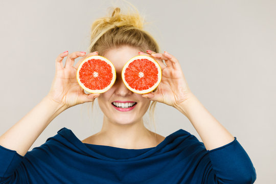 Woman holding fruit grapefruit half on eyes