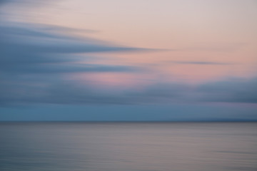 Sunrise Pink and Grey Clouds Over Silver Ocean Motion Blur
