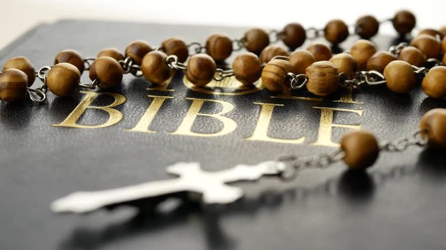 Holy bible and the cross on a wooden chain are turning