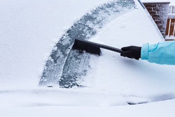 Woman cleaning snow from the car
