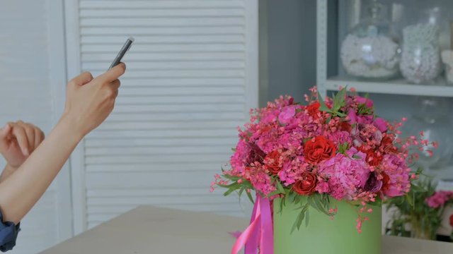 Professional floral artist, florist taking photo of her beautiful bouquet with smartphone. Photography, technology and social media concept