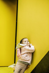 Little child in a pink suit poses near the wall