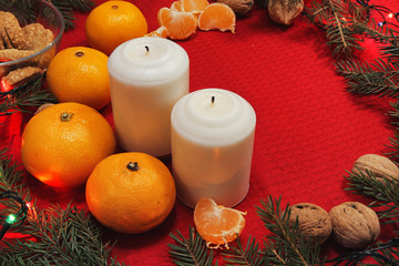Christmas tree toys on a red napkin. Mandarins and candles on th