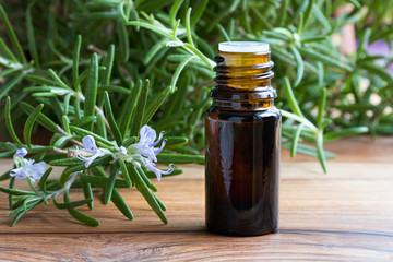 A bottle of rosemary essential oil with blooming rosemary twigs