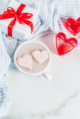 Hot chocolate with marshmallows in the shape of hearts, Valentine's Day celebration, with red cookie cutters and valentine's gift box copy space top view