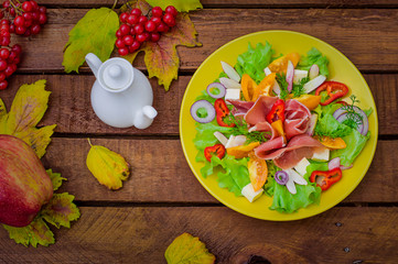 Autumn salad of jamon, lettuce, tomatoes, cheese. Wooden rustic background. Selective focus. Top view