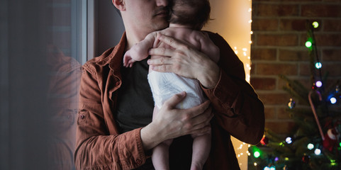 Young father holding in hands a little child in diaper.