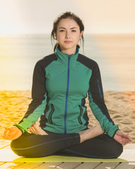 Fototapeta na wymiar woman doing yoga poses cross-legged on beach in morning