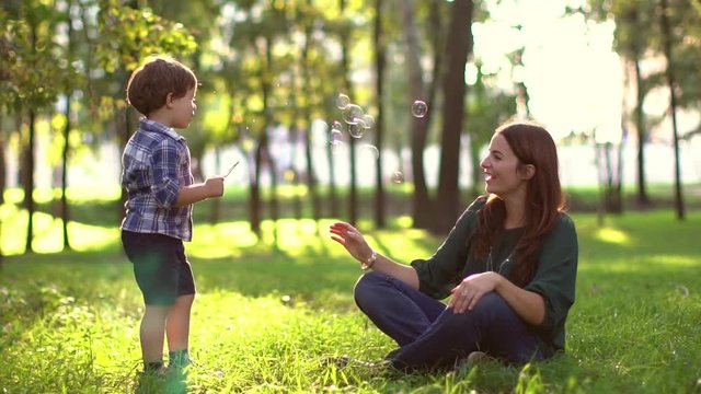 son blowing soap bubbles with mom