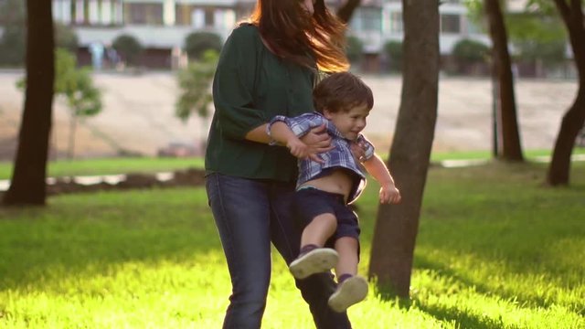 Young woman spinning with boy in slow motion