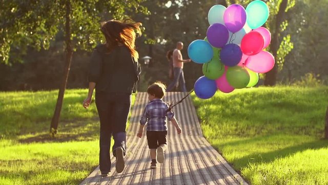 boy with balloons running away from mom