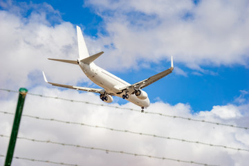 Flugzeug über Stacheldraht und blauem Himmel

