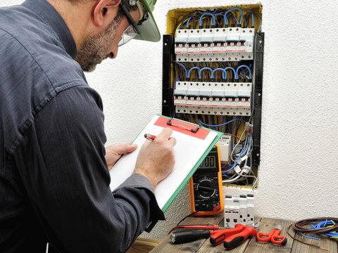 Electrician technician at work with protective helmet on a residential electric panel