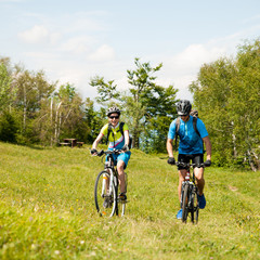 Fototapeta premium ACTIVE Young couple biking on a forest road in mountain on a spring day