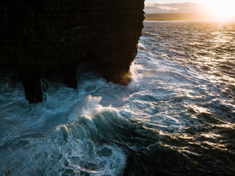 Waves crashing against Downpatrick Head sea stack standing in the atlantic ocean in Ireland during sunset