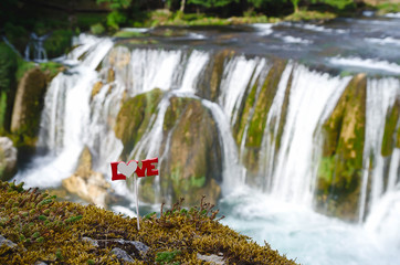love text on a stick above the waterfall