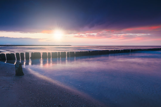 Sunset on the beach with a wooden breakwater, purple tone © dziewul