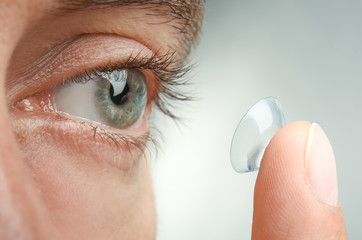 Young man putting contact lens in his eye, closeup