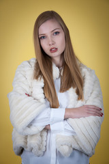 Beauty portrait of woman in fur winter jacket over yellow background