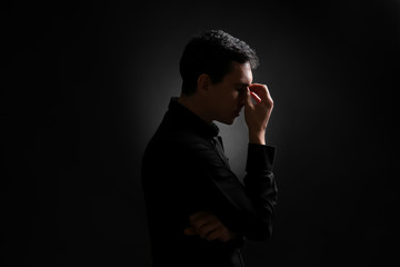 Serious young man on black background