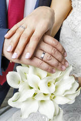 Obraz na płótnie Canvas руки супругов с обручальными кольцами на фоне цветов 