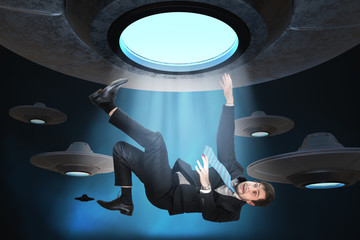 Alien abduction concept. Young man is abducted by UFO. - obrazy, fototapety, plakaty