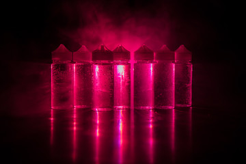 Vape concept. Smoke clouds and vape liquid bottles on dark background. Light effects