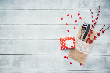 Fototapeta na wymiar Valentines day table setting with plate, knife, fork, red ribbon and hearts/ Holidays background/ Valentines day background
