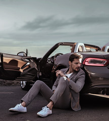 Elegant man leaning on the luxurious car