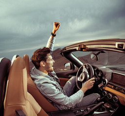 Handsome man riding a luxuriois convertible car