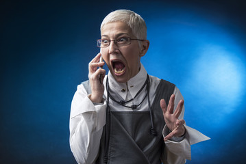 Crazy senior woman yelling at her phone, mad with customer service or another person she's talking...
