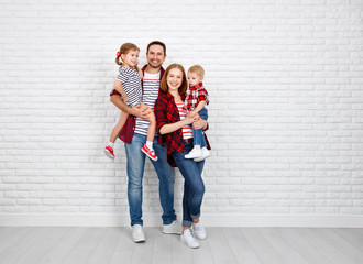 Happy family mother, father, son, daughter on a white blank wall