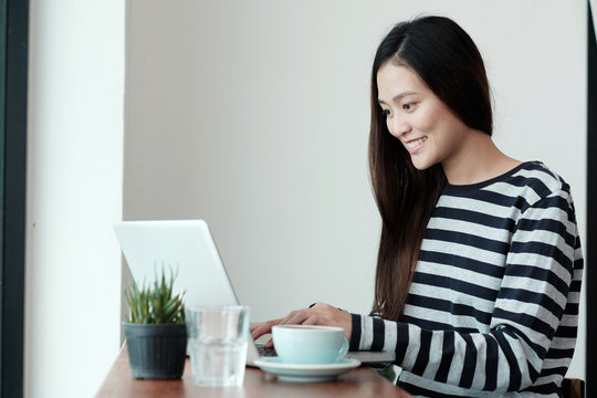 Young asian woman using laptop computer  while sitting at coffee cafe background, people and technology, lifestyles