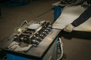 Sheet of metal in worker hands, metalworking equipment tools on industrial factory