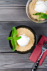 Top view close up Apple crumble dessert with vanilla ice cream, green mint on grey wooden table. fork with cake on paper