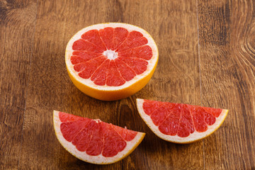 Fototapeta na wymiar three pieces of sliced grapefruit on the wooden table