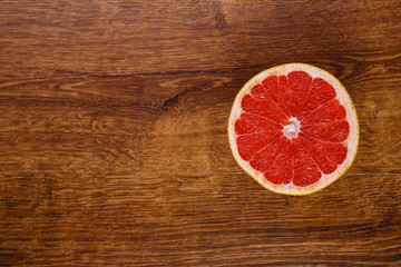 Fototapeta na wymiar one red juicy slice of grapefruit on the wooden table