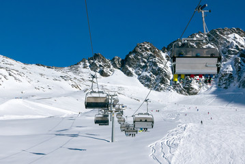 Chairlift with skierrs in high Alpine ski resort