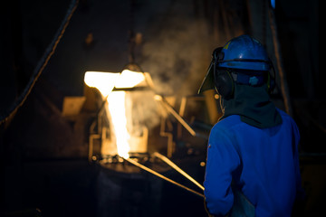 Molten metal casting, operator pouring metal casting parts from ladle in foundry