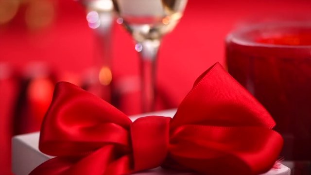 Valentine's Day romantic dinner. Date. Champagne, candles and gift box over holiday red background. Slow Motion 4K UHD video footage. 3840X2160