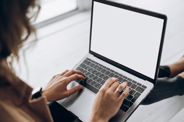 Female hands typing on the laptop. White blank laptop screen with space for text