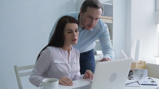 I am so sorry. Millennial office worker bringing documents and looking at a screen of a laptop than young woman saying something inappropriate and apologizing.