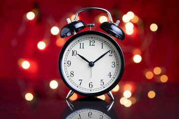 Alarm clock with party decoration light bokeh in the background using as time or wake up after party