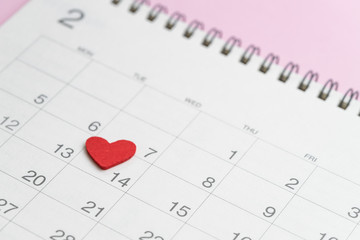 Fototapeta na wymiar Red heart shape on 14th February calendar on pink background using as romantic Valentines day concept
