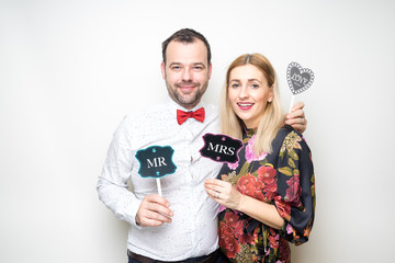 young couple funny props pose photo booth plain background
