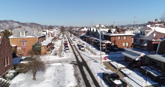 A daytime winter reverse aerial establishing shot of a quiet small town's residential neighborhood after a fresh snowfall. Pittsburgh suburbs.  	