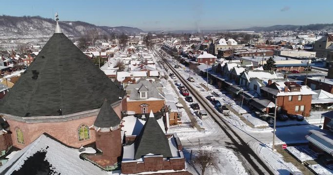 A daytime winter slow orbit aerial establishing shot of a quiet small town's residential neighborhood after a fresh snowfall. Pittsburgh suburbs.	 	