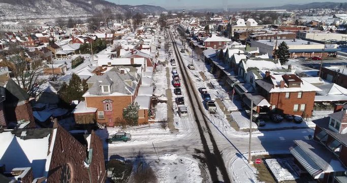 A daytime winter forward aerial establishing shot of a quiet small town's residential neighborhood after a fresh snowfall. Pittsburgh suburbs.	 	